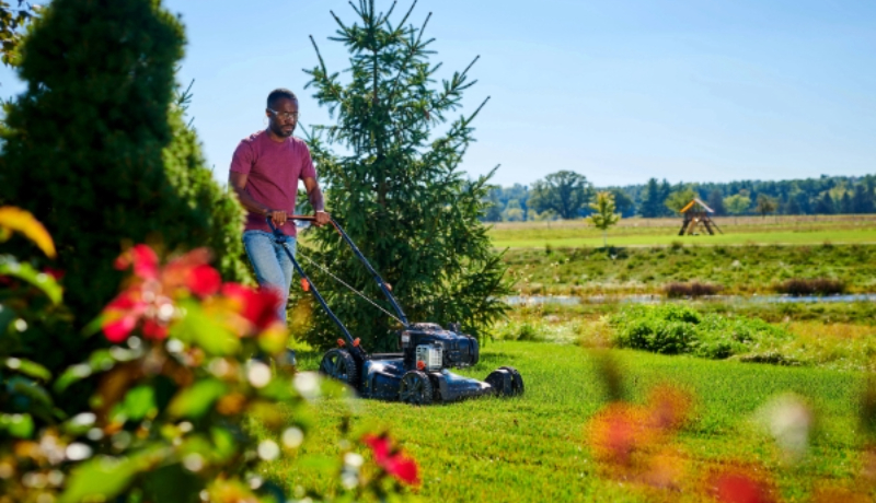 Man pushing a Senix lawn mower powered by a Briggs & Stratton E550 model engine.